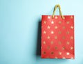 Red shopping paper bag with star pattern on blue background, space for text Royalty Free Stock Photo