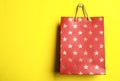 Red shopping paper bag with star pattern on yellow, space for text Royalty Free Stock Photo