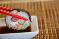 Red shopsticks holds maki sushi in air