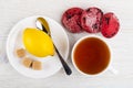 Red cookies, cup of tea, saucer with lemon,sugar, spoon on table. Top view Royalty Free Stock Photo