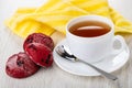 Red cookies, cup of tea, spoon on saucer, yellow napkin on table Royalty Free Stock Photo