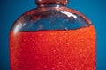 Red shower gel on blue background, closeup view