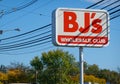 A red sign for BJ`s Wholesale club as seen on the side of a road near a club location