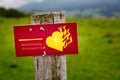 Red sign in German: Ammergau Alps meditation trail. With a yellow flaming heart