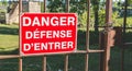 red sign placed on a rusty gate or it is written in French danger defended to enter