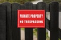 Red sign with text Private Property No Trespassing on wooden fence Royalty Free Stock Photo