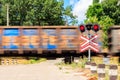 Red signal of semaphore and stop sign in front of railroad crossing with train passing Royalty Free Stock Photo