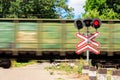 Red signal of semaphore and stop sign in front of railroad crossing with train passing Royalty Free Stock Photo