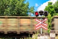 Red signal of semaphore and stop sign in front of railroad crossing with train passing Royalty Free Stock Photo