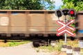 Red signal of semaphore and stop sign in front of railroad crossing with train passing Royalty Free Stock Photo