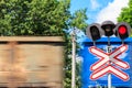 Red signal of semaphore and stop sign in front of railroad crossing with train passing Royalty Free Stock Photo