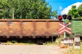 Red signal of semaphore and stop sign in front of railroad crossing with train passing Royalty Free Stock Photo