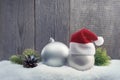 Christmas balls with Santa hat and fir twigs in the snow