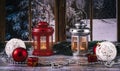 Red and silver lanterns with candles on the background of the window. Christmas balls, necklace, toys and fir branches as decor. Royalty Free Stock Photo