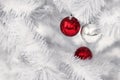 Red and silver ornament balls on white christmas tree branches.