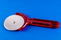A red plastic pizza cutter sits on a blue surface Royalty Free Stock Photo