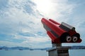 Red site seeing telescope pointing up on blue clouded sky and sea with yachts background