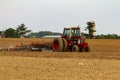 A red six wheel International 1586 tractor with cabin is plowing a blank agricultural field Royalty Free Stock Photo