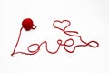 Red skein of thread against white background. Red ball of wool with red thread writes a word LOVE isolated on white. Heart and Royalty Free Stock Photo