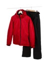 Red ski waterproof and windproof jacket and black pants on hangers isolated on white background