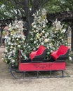 Red sleigh with heavily decorated Christmas trees in the background along Main Street in historic downtown Grapevine.