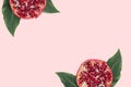 Red slices pomegranate with green leaves on the pink minimal background