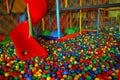 Red slide in big ball pool from playroom with colorfull net Royalty Free Stock Photo