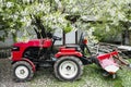 Red small modern mini tractor standing at the farm against the background of a spring landscape. Small agricultural Royalty Free Stock Photo