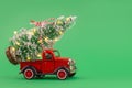 Red small retro toy truck with sparkling Christmas tree lights on truck body on green background. Royalty Free Stock Photo