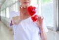 Red smiling heart held by smiling female nurse`s hands in health care hospital or clinic. Professional, Specialist, Experience