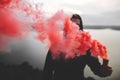 Red smoke bomb. Blurred image of ultras hooligan holding  smoke bomb in hand, standing on top of rock mountain with amazing view Royalty Free Stock Photo