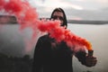 Red smoke bomb. Blurred image of ultras hooligan holding  smoke bomb in hand, standing on top of rock mountain with amazing view Royalty Free Stock Photo