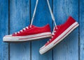 Red sneakers hanging on a wooden blue background Royalty Free Stock Photo