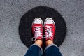 Red canvas sneakers shoes on woman`s feet on the asphalt with black circle Royalty Free Stock Photo