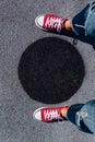 Red canvas sneakers shoes on woman`s feet on the asphalt with black circle Royalty Free Stock Photo