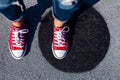 Red canvas sneakers shoes on woman`s feet on the asphalt with black circle Royalty Free Stock Photo