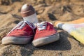 Red sneakers with white shoelaces on a sandy beach with shaker and towel left on the beach. people going for a fast swim in the Royalty Free Stock Photo