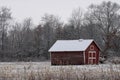 Red snow-covered barn in the countryside surrounded by naked trees in winter Royalty Free Stock Photo