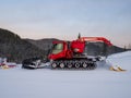Red snow groomers clean the slope of the mountain in the mountain ski resort of Gornaya Salanga