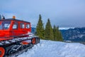 Red Snowcat and Cloudy Sky Over Winter Mountains Royalty Free Stock Photo