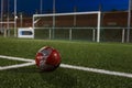 A red soccer ball is crossing the white lines of the football field markings. Royalty Free Stock Photo