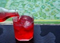 Red soda pouring from bottle to drink glass with ice Royalty Free Stock Photo