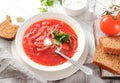 Red soup, borscht with sour cream and herbs in a white plate, bread , spoon on a white wooden table Royalty Free Stock Photo