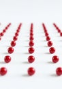 Red spheres arranged in straight, parallel rows on a white surface. The spheres are highly polished, Royalty Free Stock Photo