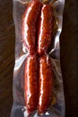Red spicy spanish mediterranean chorizo sausages in plactic vacuum packed wooden table background