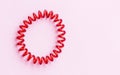 Red spiral rubber bands for hair on a pink background close-up, copy space for text Royalty Free Stock Photo