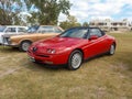 Red sport Alfa Romeo Spider Type 916 roadster early 1990s parked on the grass. Classic car show Royalty Free Stock Photo