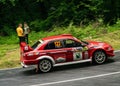 Red sports car driving along a scenic road, while participating in a hill climb race