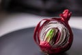 Red sprouted onions cut in half on a black plate Side view. Place for your text. Concept photo Royalty Free Stock Photo