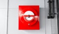Red square fire alarm with a circular red and white button on a wall device Royalty Free Stock Photo